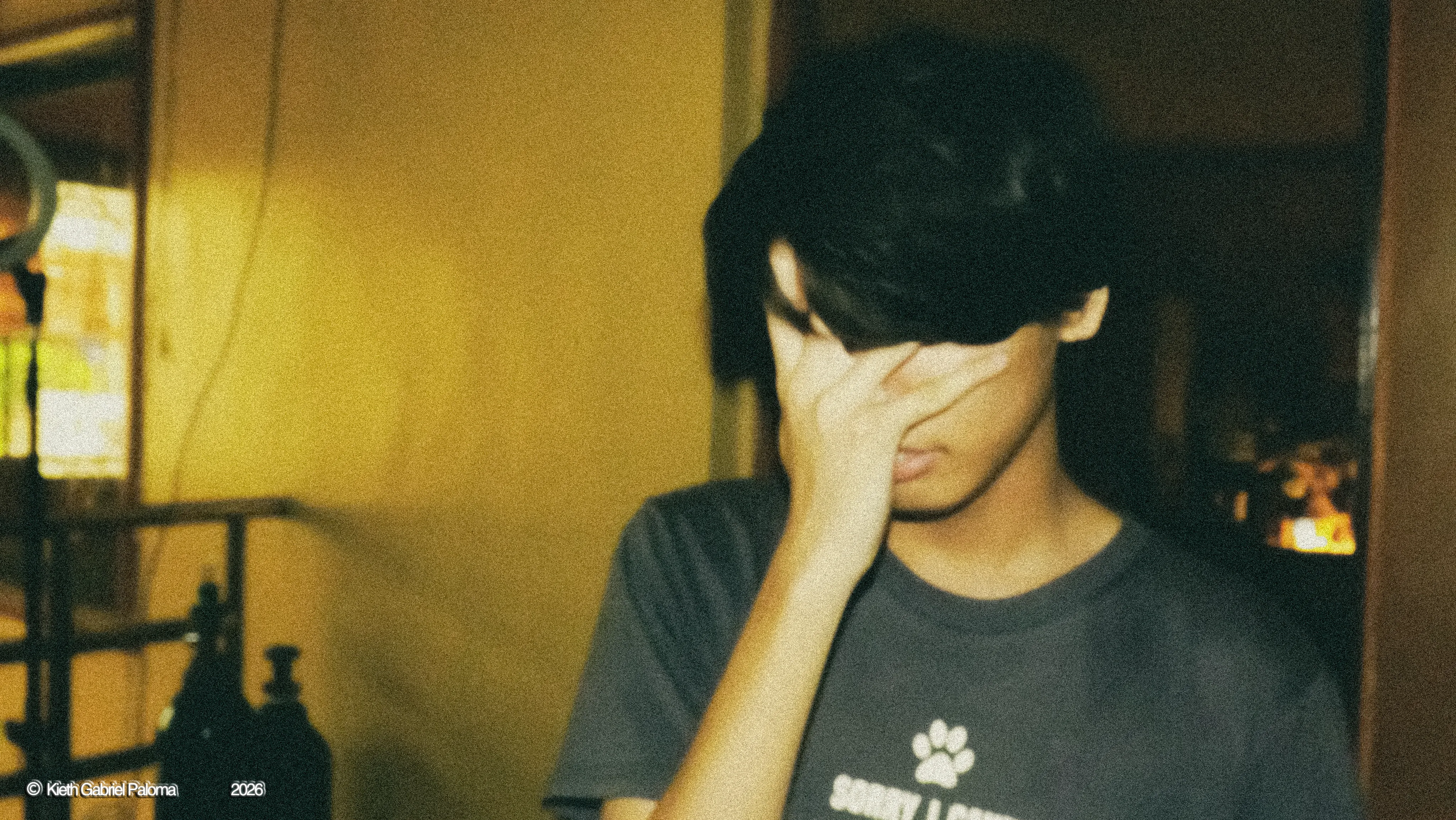 jucu turned away in warm lamplight, one hand covering his face